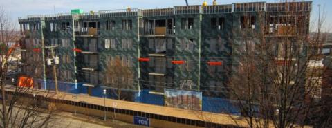 Front face of under construction building. There is scaffolding and building material scattered around.
